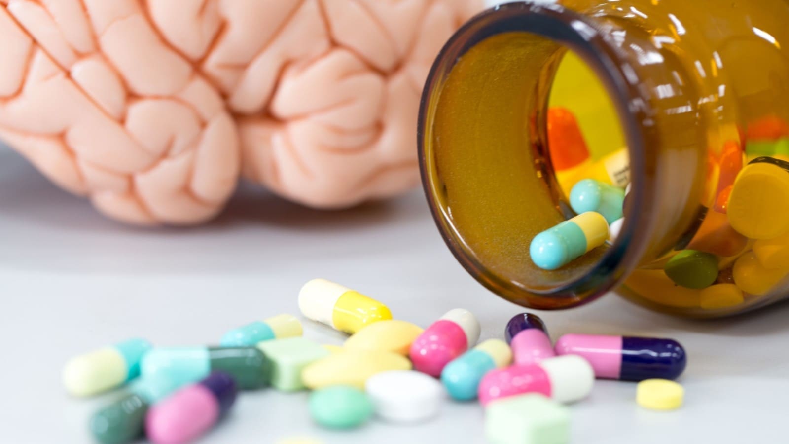 Different medicine pills on the table with a brain model